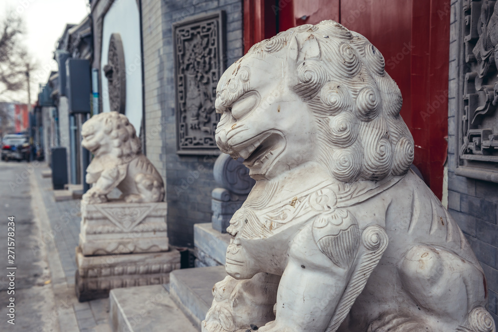 Lion sculptures in front of a house entrance in alley called hutong - traditional residential area in Beijing, capital city of China