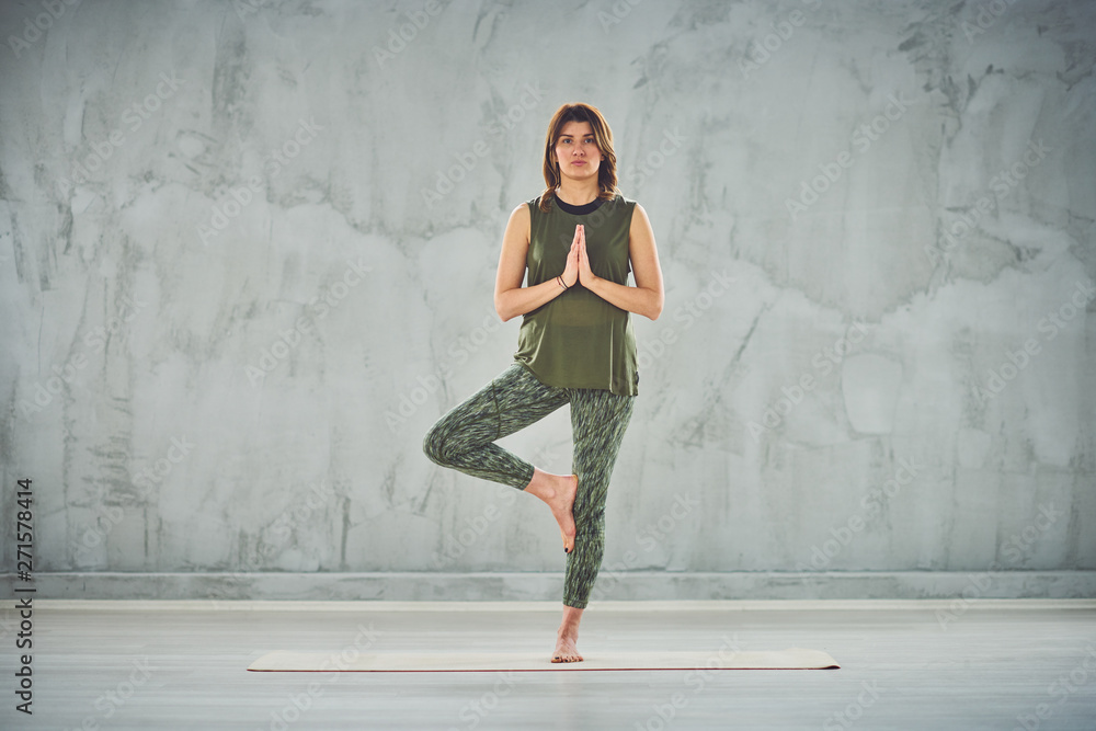 Charming brunette standing on the mat in half lotus pose. Charming brunette standing on the mat in half lotus pose.
