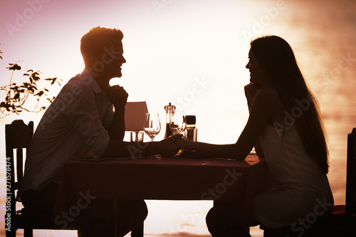 People, vacation, love and romance concept. Young couple enjoying a romantic dinner on beach.