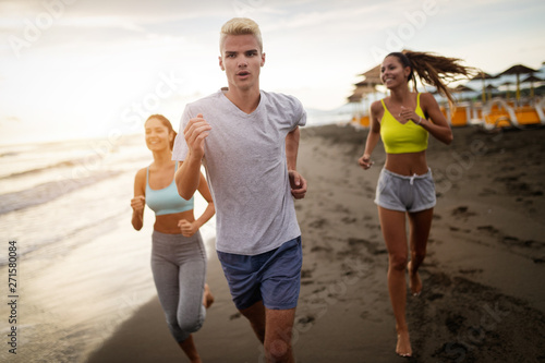 Group of young friends running and exercising on the beach