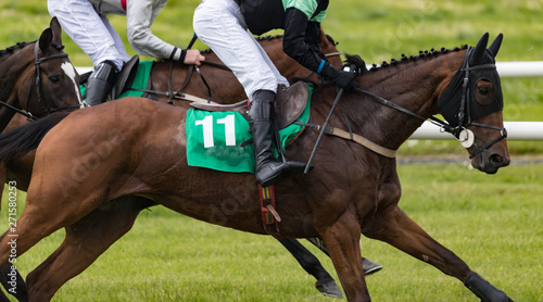 Close up on group of jockeys and race horses racing on track