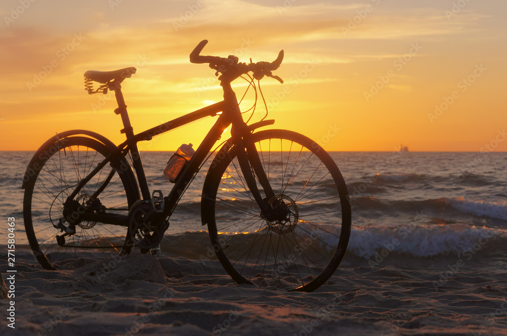 Bike and sunset by the sea. Black bike by the sea.