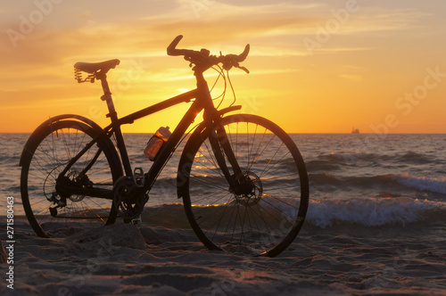 Bike and sunset by the sea. Black bike by the sea.