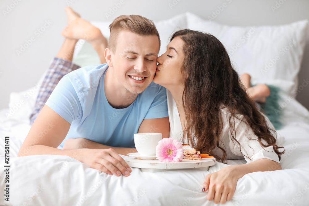 Cute young couple having breakfast in bed