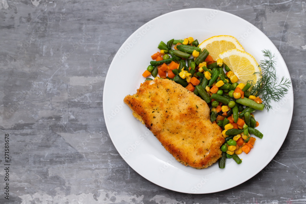 fried chicken with boiled vegetables and lemon on white dish fried chicken with boiled vegetables and lemon on white dish