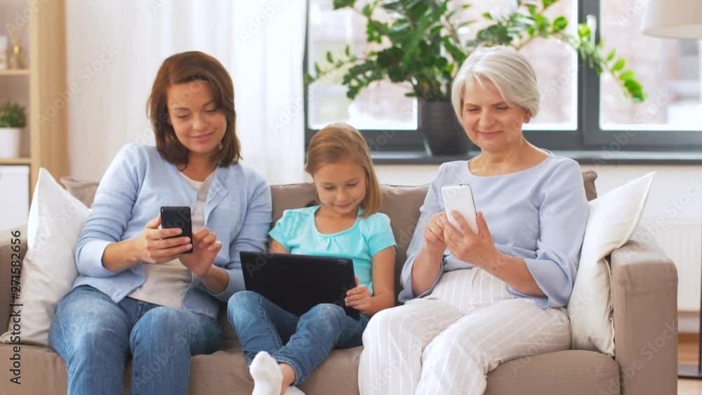 family, technology and three generations concept - happy mother, daughter and grandmother with tablet computer and smartphones at home family, technology and three generations concept - happy mother, daughter and grandmother with tablet computer and smartphones at home