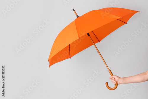 Female hand with umbrella on light background photo