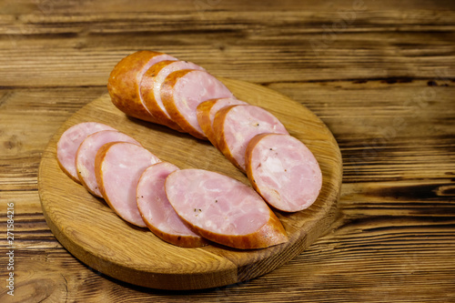 Sliced smoked sausage on cutting board on wooden table