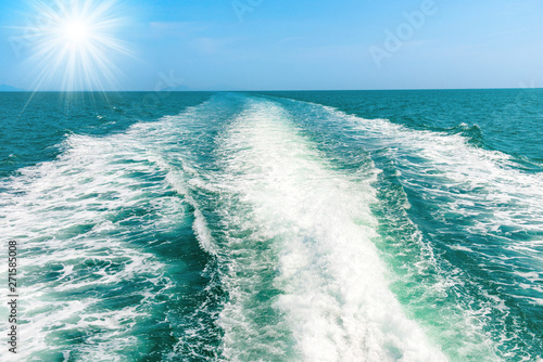 Wave from speed boat on blue sea with sun rays on sky © Pavlo Vakhrushev