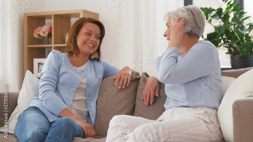 family, generation and people concept - happy smiling senior mother talking to adult daughter at home