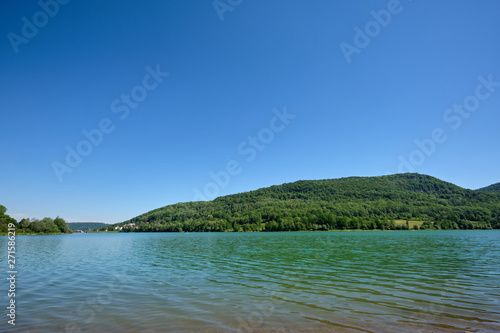 The beautiful lake called "Happurger See" (also "Happurger Stausee") in the Hersbruck Switzerland with the mountain called "Houbirg" in the background on a perfect sunny summer day with blue sky
