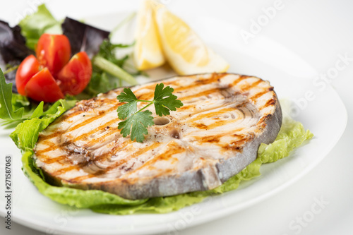 Grilled wordfish with salad and lemon on the white plate