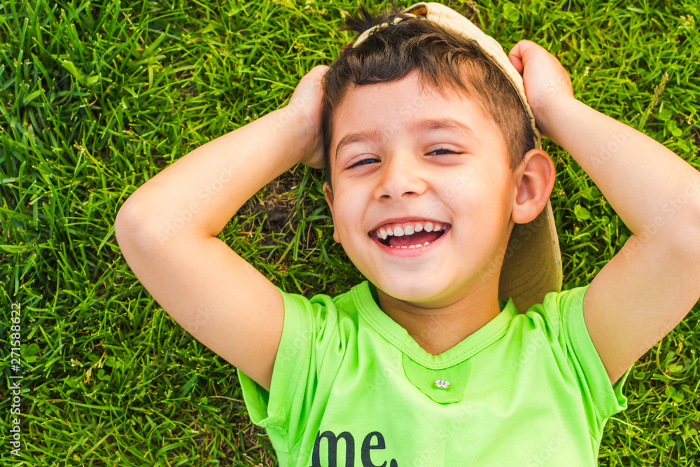 cheerful smiling boy lying on the grass in the summer cheerful smiling boy lying on the grass in the summer
