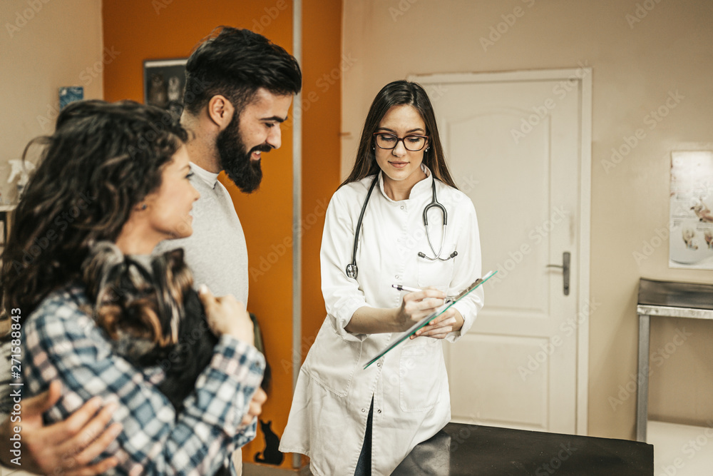 Obraz premium Young couple with their Yorkshire terrier at veterinary.