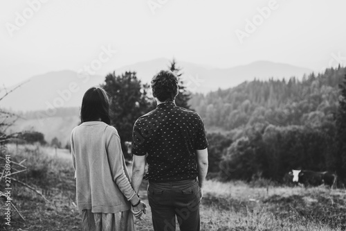 Back view Couple travelers. Man and woman looking on mountains and clouds. Love and travel. Lifestyle concept. Black and white photo.