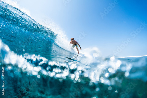 Surfer rides tropical, crystal clear ocean wave