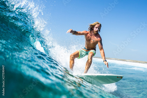Caucasian, long haired surfer rides the ocean wave on the Jailbreaks surf spot in Maldives photo