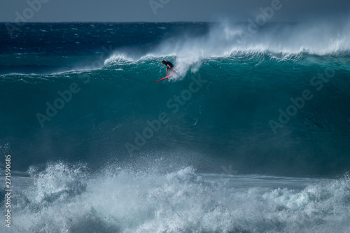 Photography Surfer rides giant wave at the famous Waimea Bay surf spot located on the North