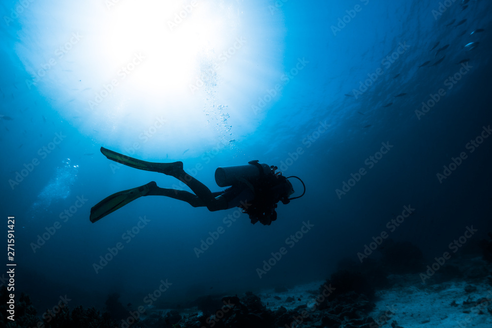 Silhouette of the scuba diver swimming alone in the depth