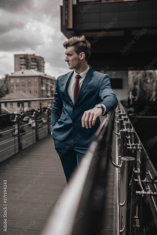 Portrait of handsome fashion businessman model dressed in elegant suit posing on street background. City urban style. Success lifestyle Portrait of handsome fashion businessman model dressed in elegant suit posing on street background. City urban style. Success lifestyle