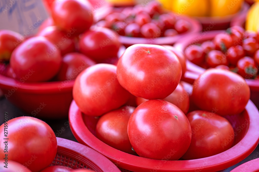 Delicious fresh tomatoes fruit vegetable food in red plastic basket at tradition market afternoon, Seoul, South Korea, harvest concept, close up. Delicious fresh tomatoes fruit vegetable food in red plastic basket at tradition market afternoon, Seoul, South Korea, harvest concept, close up.