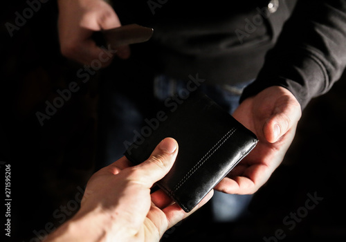 Man holding in hands and demanding money with wallet. Robber in black sweater. Dangerous people.