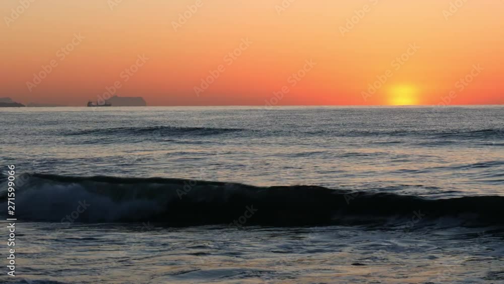 A beautiful sunrise in time lapse on a beach in Alicante in June on the Mediterranean Sea. On the horizon is a ship to see. A beautiful sunrise in time lapse on a beach in Alicante in June on the Mediterranean Sea. On the horizon is a ship to see.