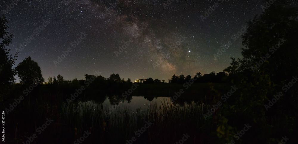Fototapeta premium Stars in the sky at night. Panoramic view of the bright Milky Way over the lake. Photographed with a long exposure.