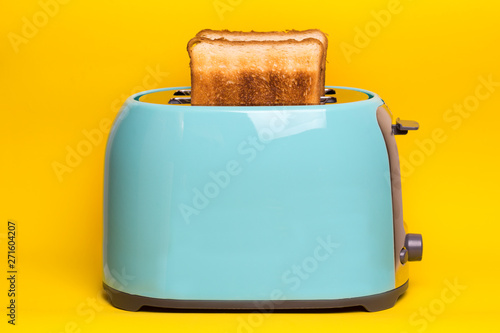 cyan color toaster on a yellow background photo