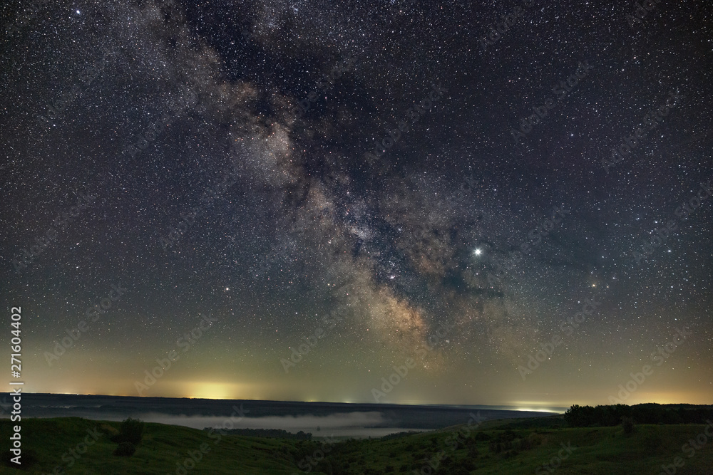 Fototapeta premium Stars in the sky at night. Bright milky way over the horizon with fog. Photographed with a long exposure.