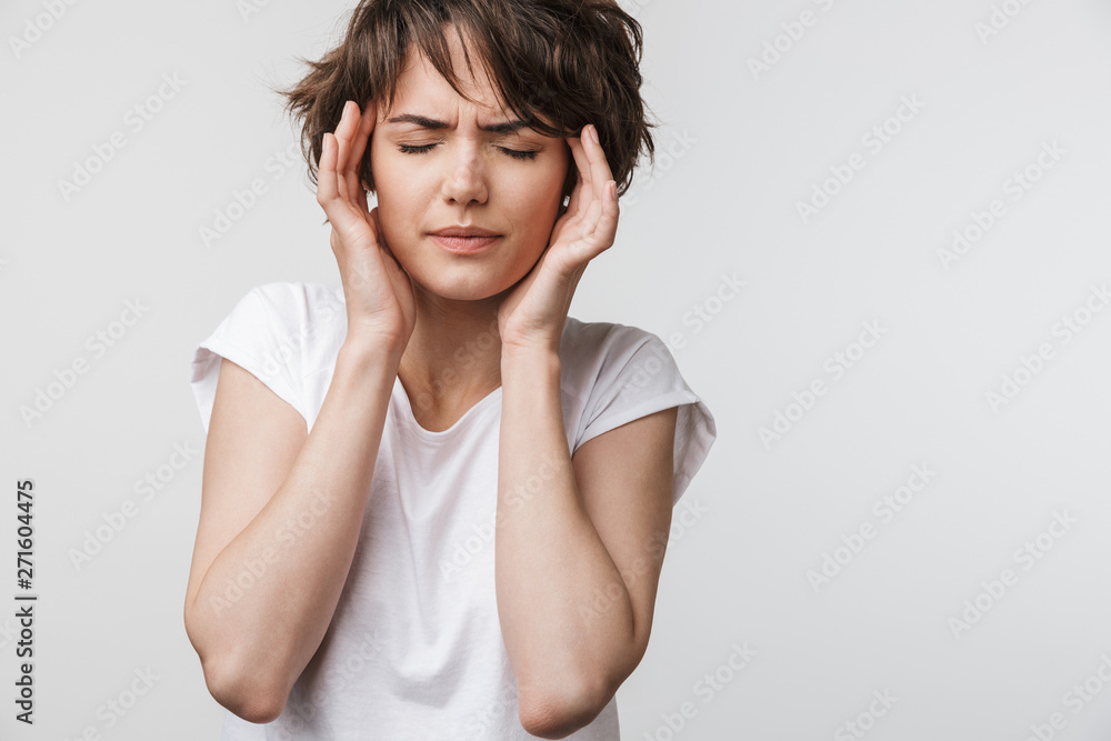 Pretty sad woman posing isolated over white wall background with headache. Pretty sad woman posing isolated over white wall background with headache.