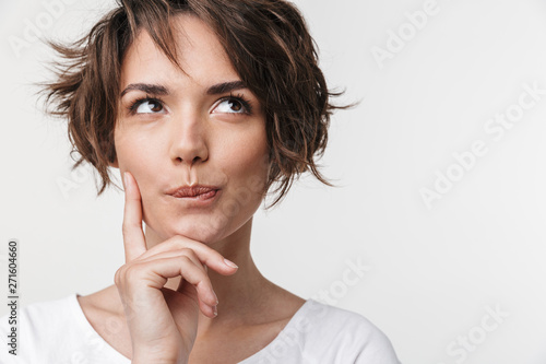 Fototapeta Beautiful young pretty thinking thoughtful woman posing isolated over white wall background