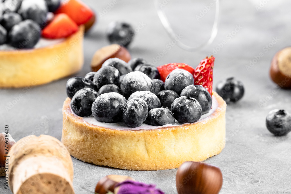 Blueberry and strawberry shortcake. There are hazelnuts, roses and wine corks on the table. Stone background. Blueberry and strawberry shortcake. There are hazelnuts, roses and wine corks on the table. Stone background.