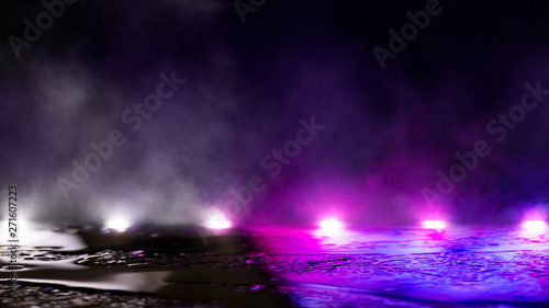 Fototapeta Naklejka Na Ścianę i Meble -  Empty street scene background with abstract spotlights light. Night view of street light reflected on water. Rays through the fog. Smoke, fog, wet asphalt with reflection of lights. Blue and pink neon