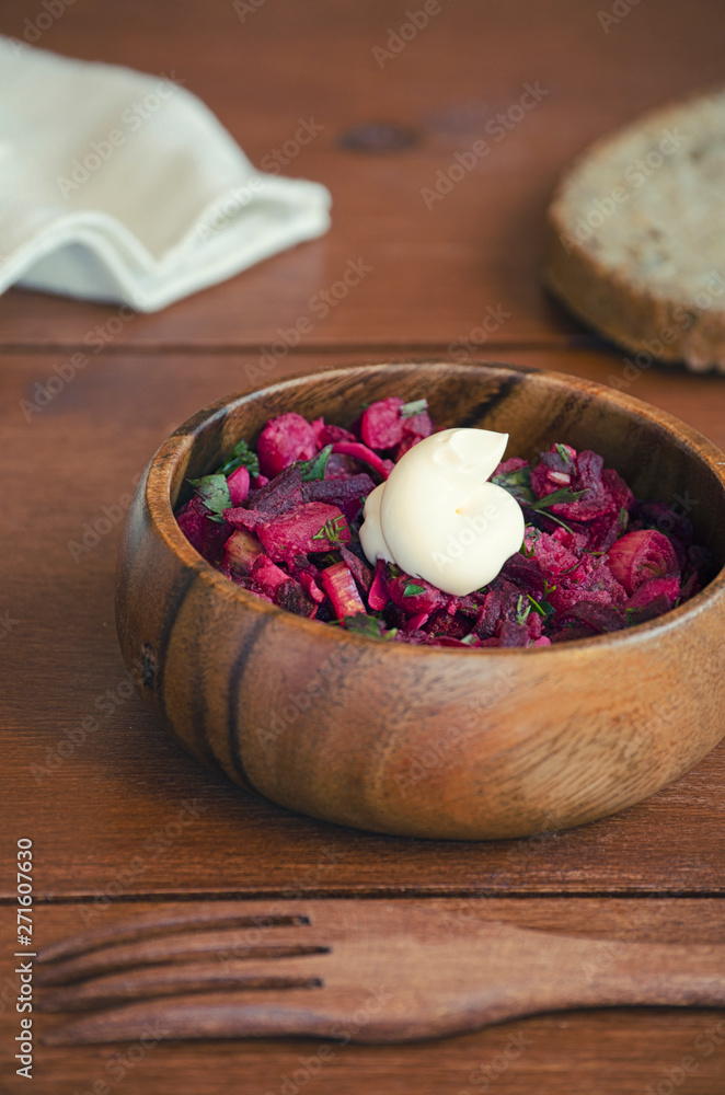fresh vegetable vegetarian salad with sauce in wooden bowl with wooden fork on wooden table, Russian salad vinaigrette, closeup 45 view fresh vegetable vegetarian salad with sauce in wooden bowl with wooden fork on wooden table, Russian salad vinaigrette, closeup 45 view