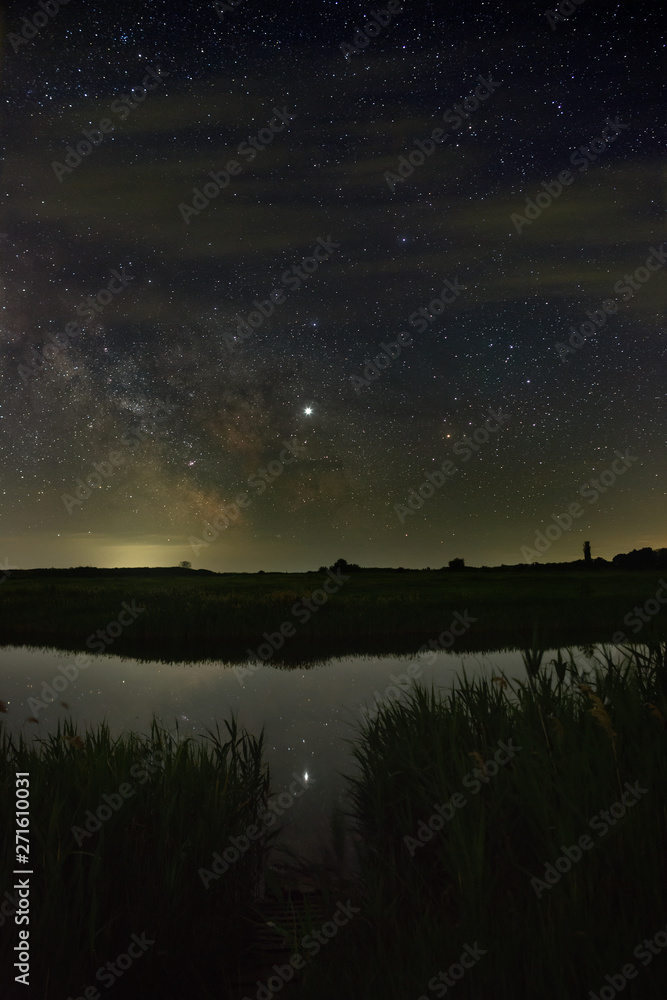Bright stars of the Milky Way galaxy over the river in the night sky. Outer space photographed with long exposure.