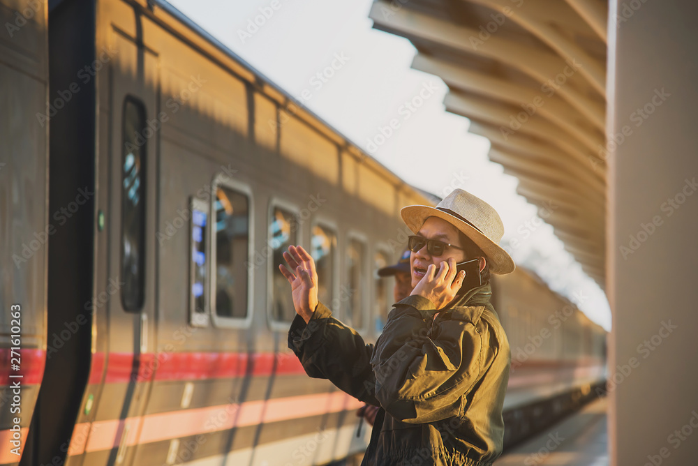 Obraz premium Travel man wait train at platform - people vacation lifestyle activities at train station transportation concept