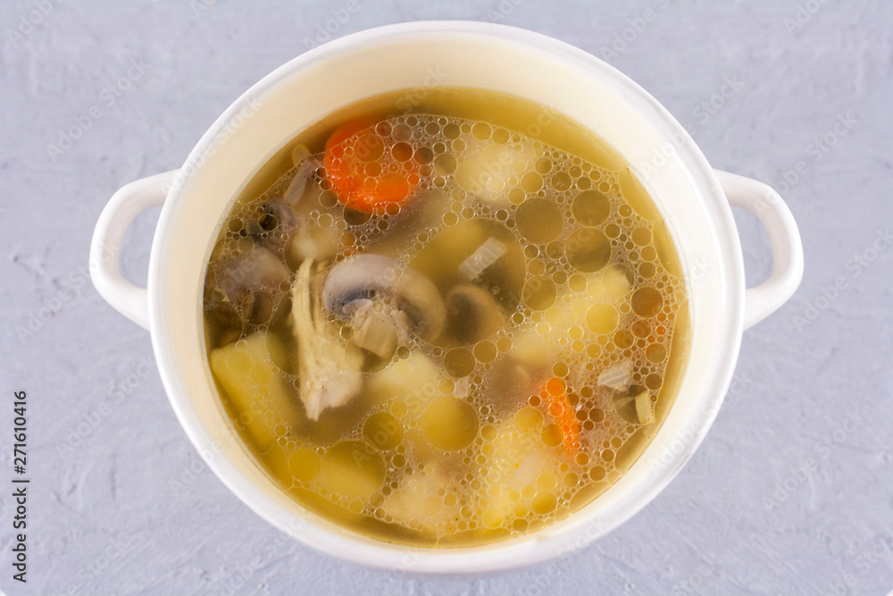 Bowl of chicken broth with champignons mushrooms close-up on gray background Bowl of chicken broth with champignons mushrooms close-up on gray background