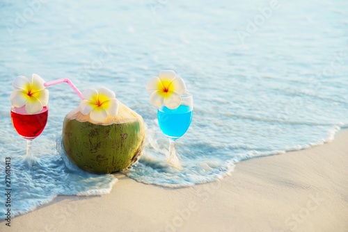 Cocktail glasses with coconut and pineapple on clean sand beach - fruit and drink on sea beach backgroudn concept