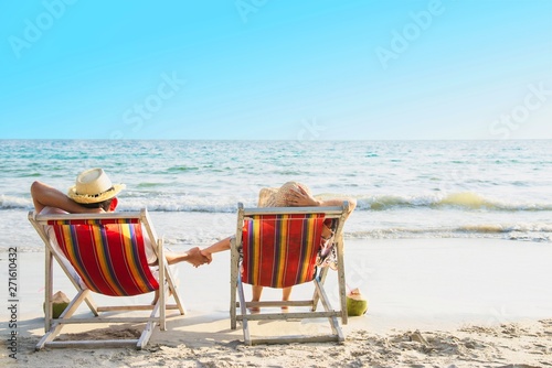 Relax couple lay down on beach chiar with sea wave background - man and woman have vacation at sea nature concept