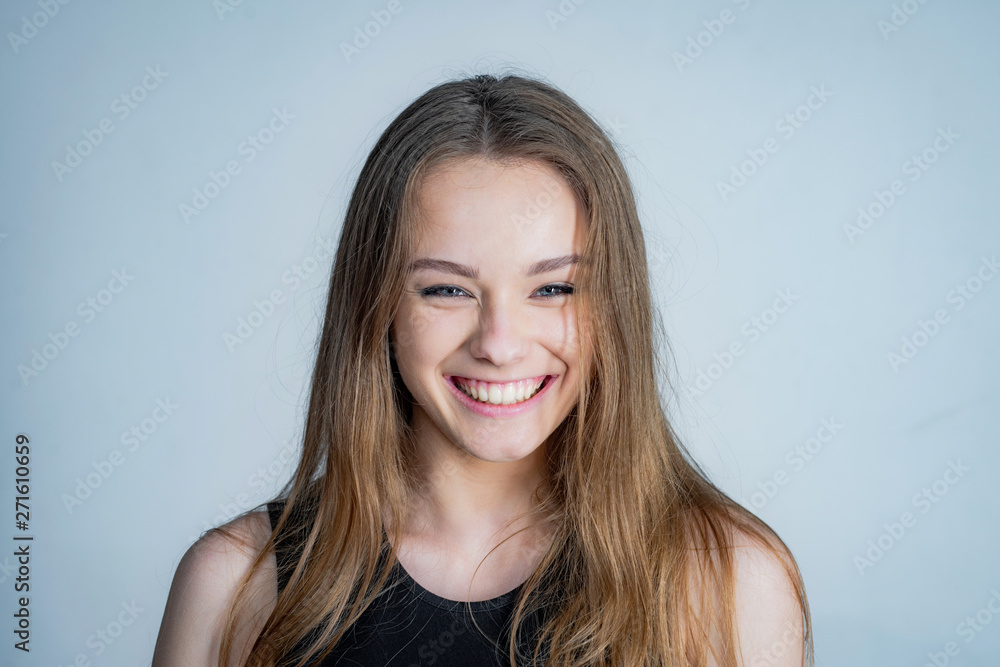 Happy girl face portrait. Close up portrait of young cheerful beautiful girl with long hair in casual shirt smiling looking in camera with happy face expression. Happy girl face portrait. Close up portrait of young cheerful beautiful girl with long hair in casual shirt smiling looking in camera with happy face expression.