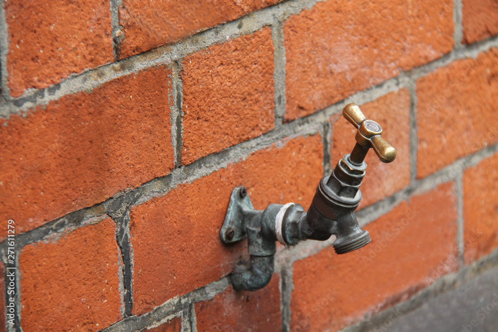 An Outdoor Wall Mounted Brass Water Tap. An Outdoor Wall Mounted Brass Water Tap.