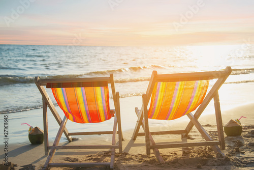 Couple relax chair on sand beach with warm sunset - vacation in beautiful sea nature concept