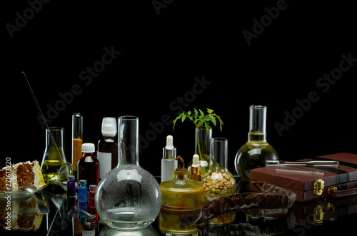 Medical jars with reagents and a plant with a leather suitcase on a black background