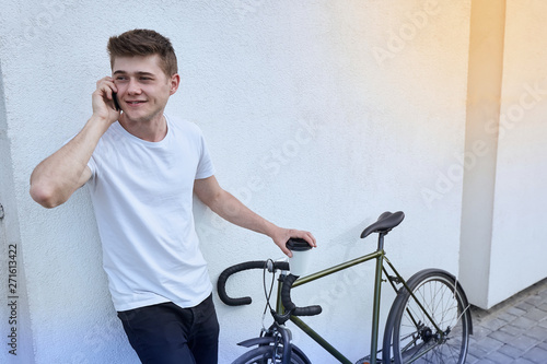 Handsome hipster man posing with bicycle in the city.