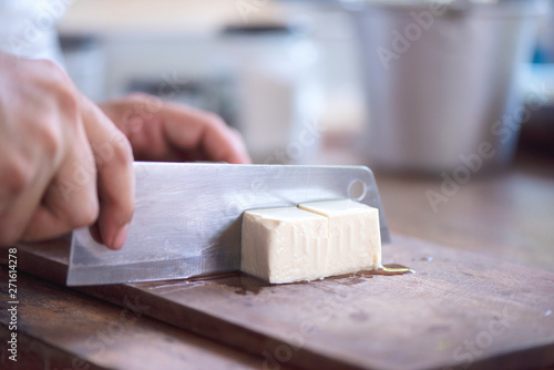 chef has a kitchen knife in his hand and cuts the tofu in a square shape