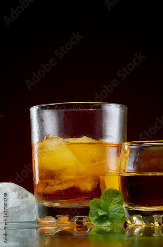 Strong alcohol in a transparent glass with ice on a red background