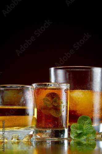Alcoholic drink in glasses with ice and mint on red background
