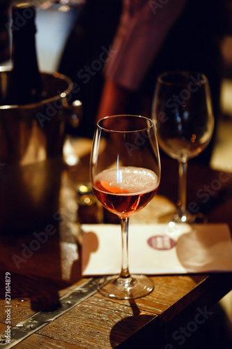 Moscow, Russia-March 30, 2019: Wine tasting. On the wooden table is a glass filled with pink champagne, a bucket for cooling bottles, brochures and empty wine glasses.