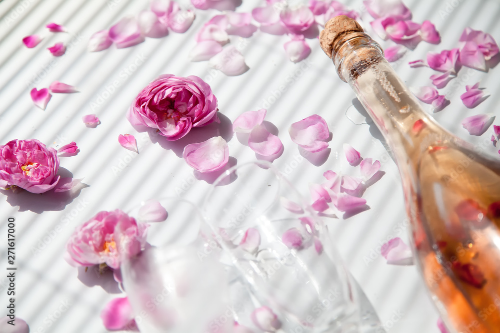 bottle of pink sparkling wine and glass on a white background with pink roses bottle of pink sparkling wine and glass on a white background with pink roses